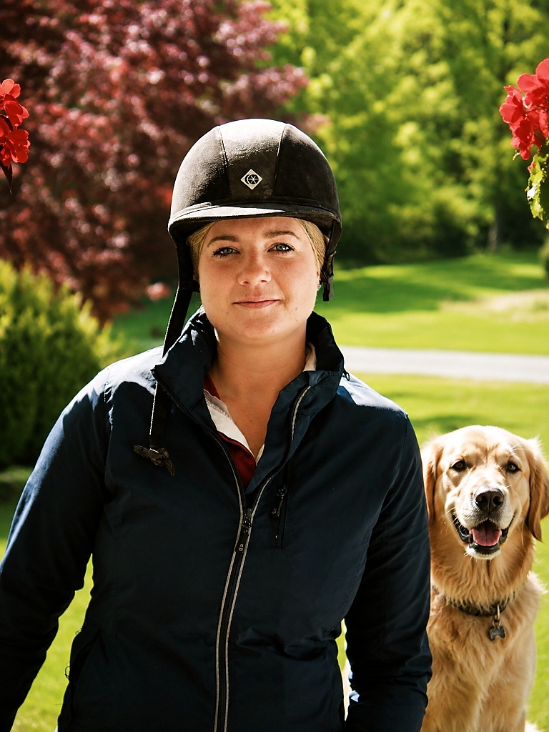 Carolyn Sabolis-Hall (CJ) in riding attire with her loyal, attentive canine companion outdoors.